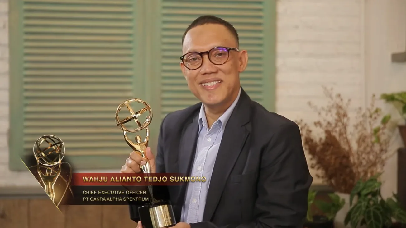 Wahju Alianto Tedjo Sukmono tersenyum memegang trofi emas berbentuk bola dunia, dengan keterangan namanya sebagai Chief Executive Officer PT Cakra Alpha Spektrum